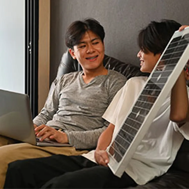 couple holding a laptop and a solar panel