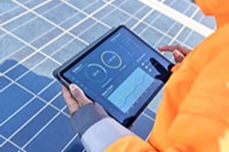 over the shoulder view of a field technician holding a digital tablet showing a solar power panel monitoring app