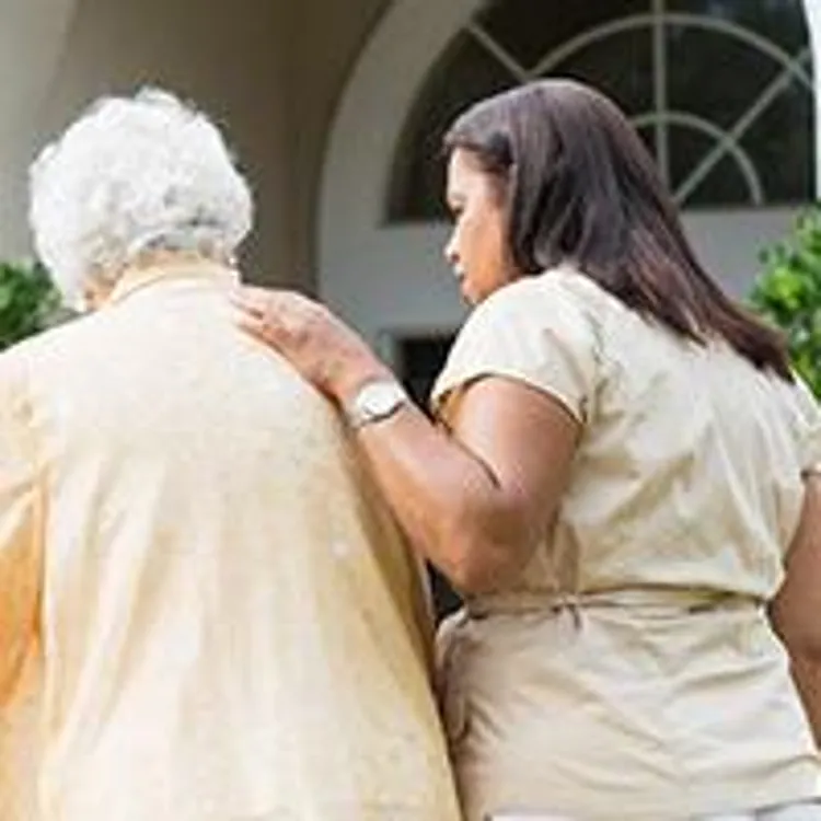 older woman walking with the help of a nurse