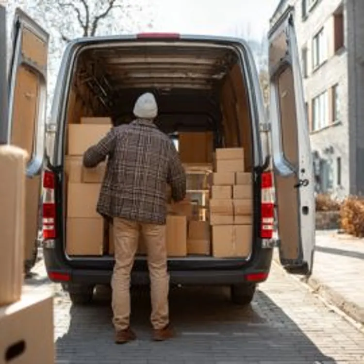 a man loading cardboard boxes inside a van