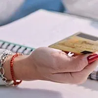 woman typing with credit card in hand