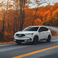 white acura mdx on a road with trees in autumn colors