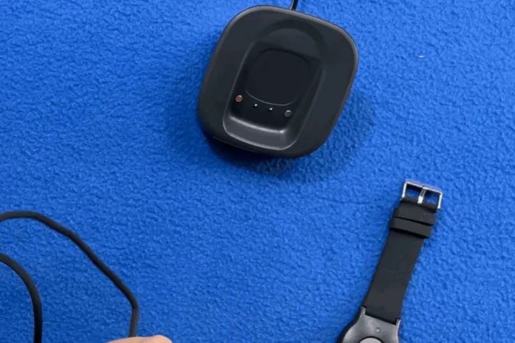 Hands placing the ADT On-the-Go pendant on its charging dock as the ring light comes on