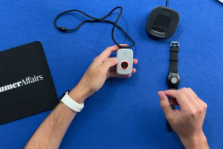 Hand pressing the call button on the ADT On-the-Go pendant as its ring lights red