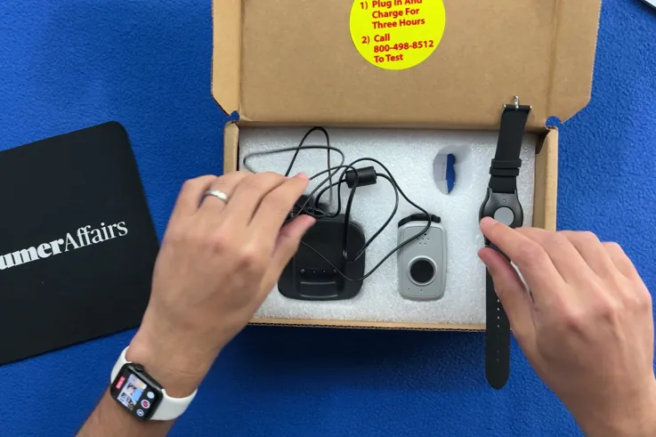 Opened ADT On-the-Go shipping box showing the pendant, wristband and charging base in foam packaging