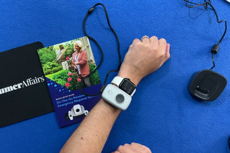 ADT On-the-Go wristband worn on the wrist next to the pendant's quick setup guide