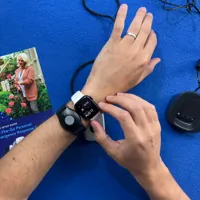 Person wearing a smartwatch and emergency response wristband next to a quick step guide and charging dock