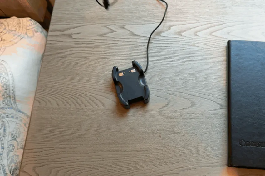 Hand setting the LifeBeacon pendant into its charging cradle on a nightstand