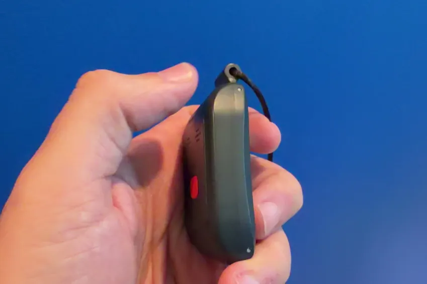 Side view of the Alert1 LifeBeacon pendant held between fingers, showing its thickness