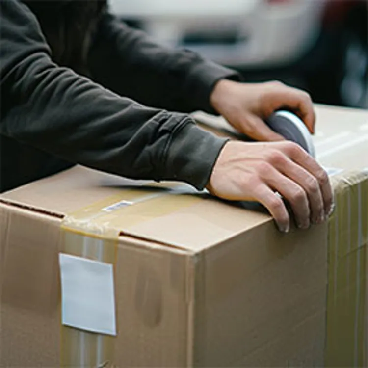 man closing a packing box with tape