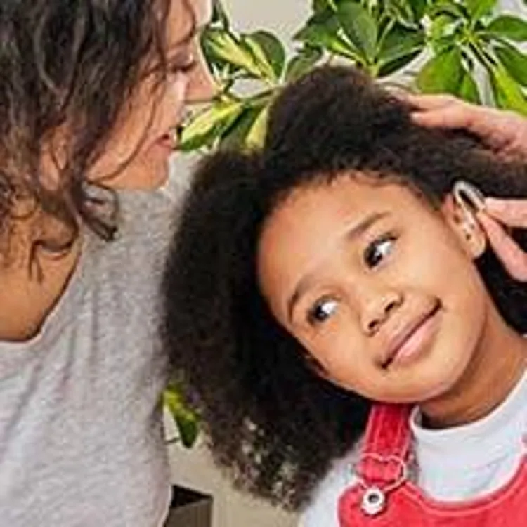 audiologist inserting hearing aid into childs ear