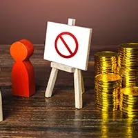 Wooden figures facing a small easel with a prohibition sign next to stacks of gold coins on a wooden table.