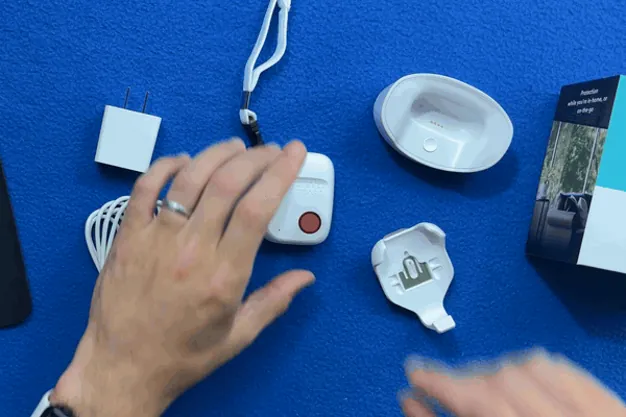 Overhead view of a finger pressing the red help button on the SOS All-in-One 2 pendant