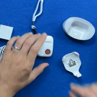 Overhead view of a finger pressing the red help button on the SOS All-in-One 2 pendant