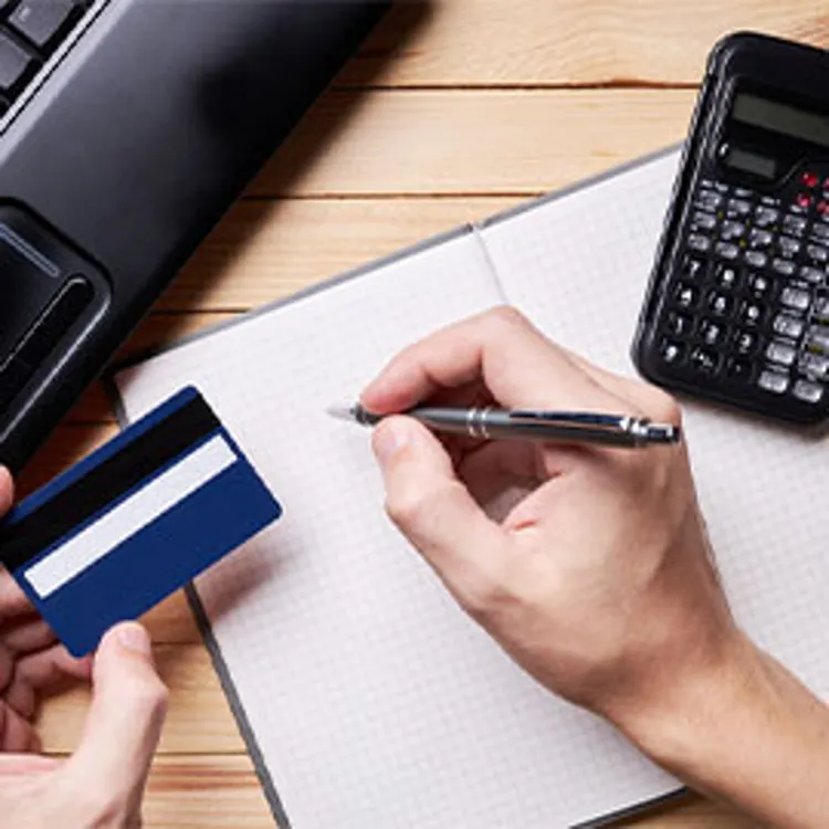 person holding credit card and pen making calculations