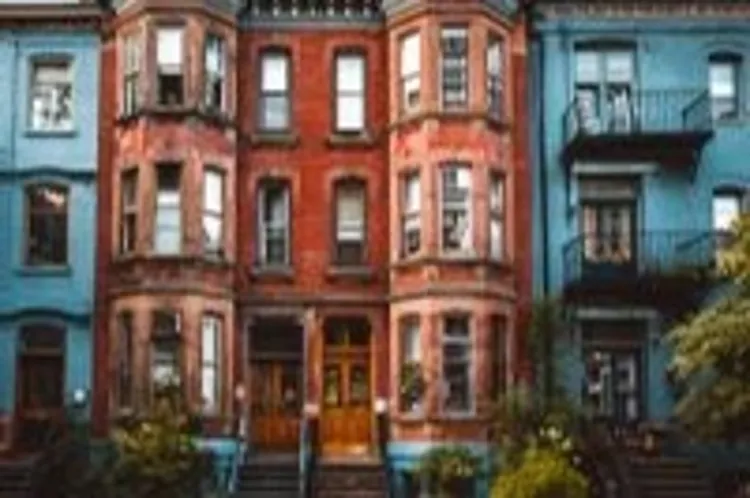 street view of a row of vintage townhouses with red brick and blue façades