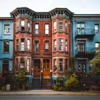 street view of a row of vintage townhouses with red brick and blue façades