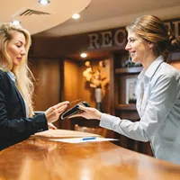 woman paying contactless with a credit card at the hotel reception desk