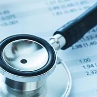 calculator and stethoscope on top of loan papers