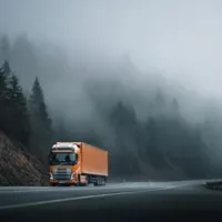 an orange container van moving through thick fog