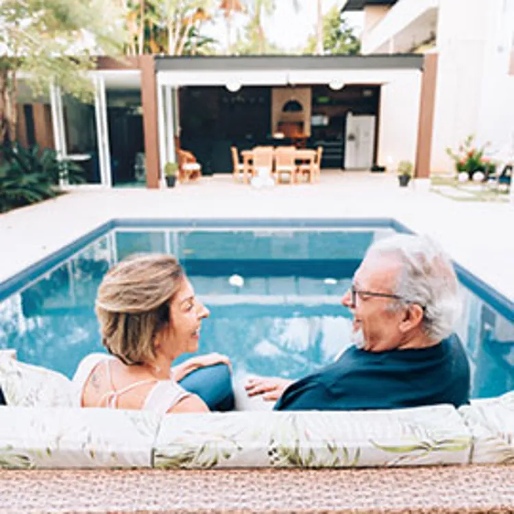 happy couple with swimming pool in background smiling talking with loan officer
