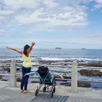 mother looking at child in wheelchair enjoying the sea view