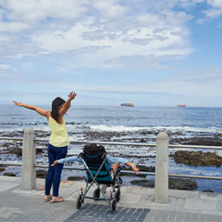 mother looking at child in wheelchair enjoying the sea view