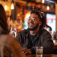 a guy sitting at a bar and smiling at the person in front of him