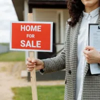 real estate agent holding a for sale sign