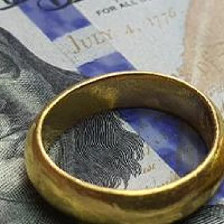 Wedding rings on top of hundred dollar bills