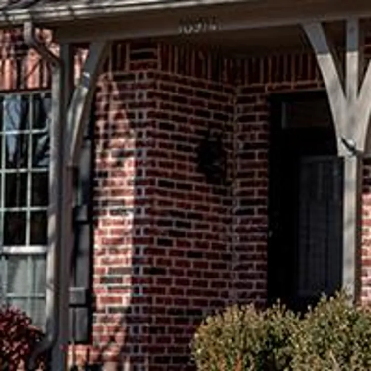 woman standing in front of home with home security technician