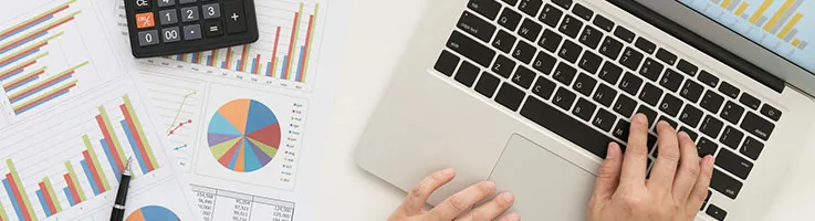 man working on a laptop surrounded by charts