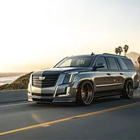 A gray cadillac escalade on a road by the water
