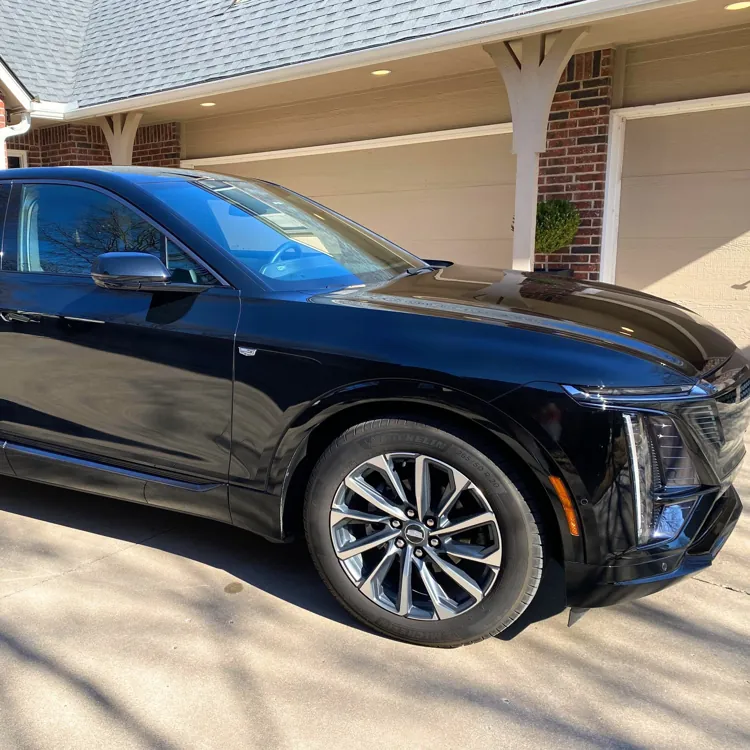 Black SUV parked in a driveway on a sunny day with a brick house in the background.