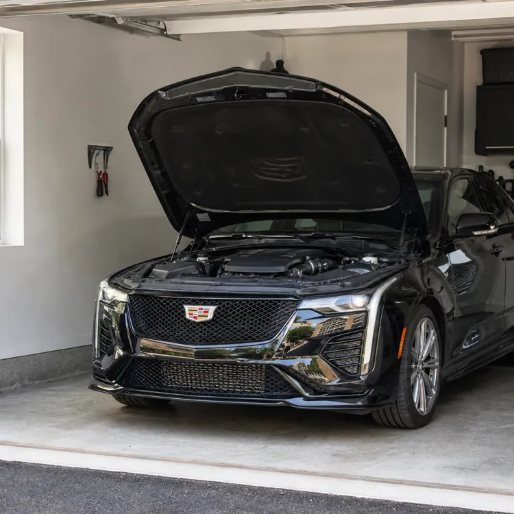 Black sedan with hood open parked inside a residential garage