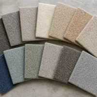 Assorted carpet samples in various neutral and blue shades arranged on a concrete surface