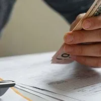 man holding cash and using calculator