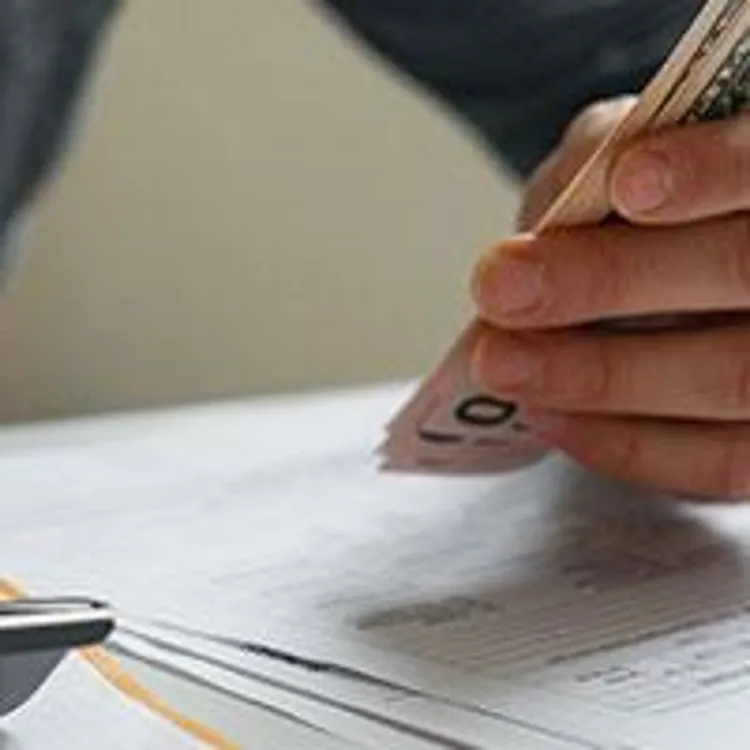 man holding cash and using calculator
