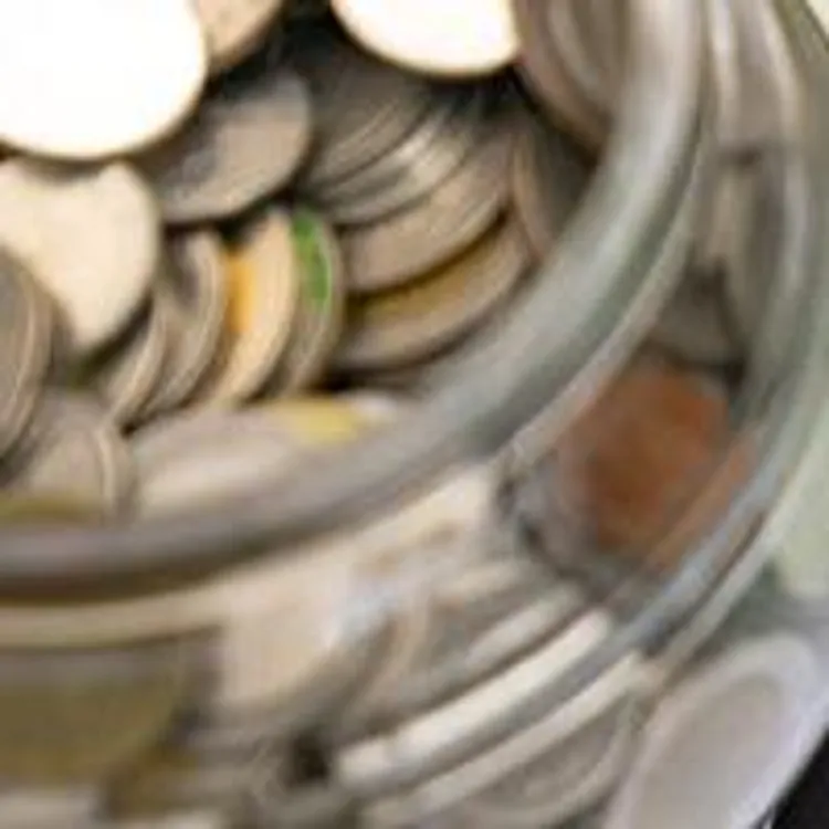 jar of coins beside piggy bank calculator and bank statement