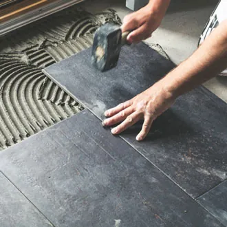 worker carefully placing ceramic floor tiles on adhesive surface