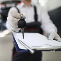 hands holding car key and clip board with paper and pen