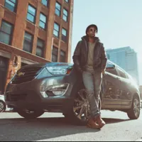 young man leaning against a parked car