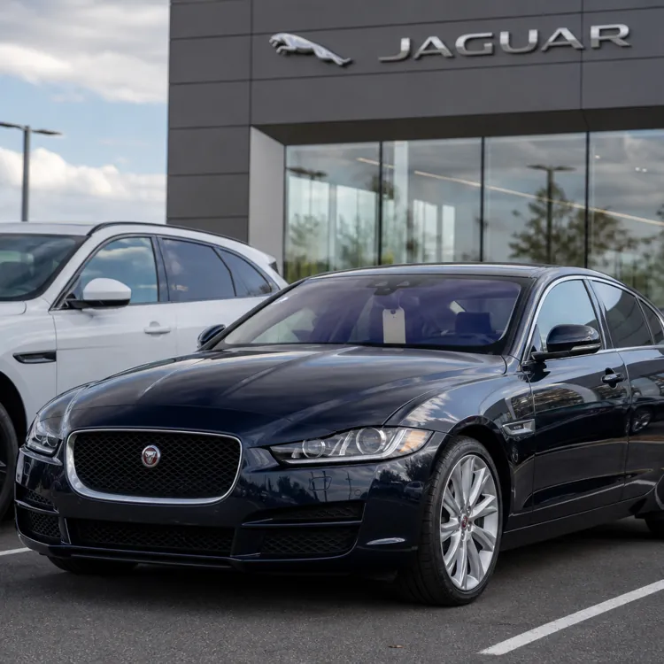 Black Jaguar sedan parked in front of dealership with other cars nearby