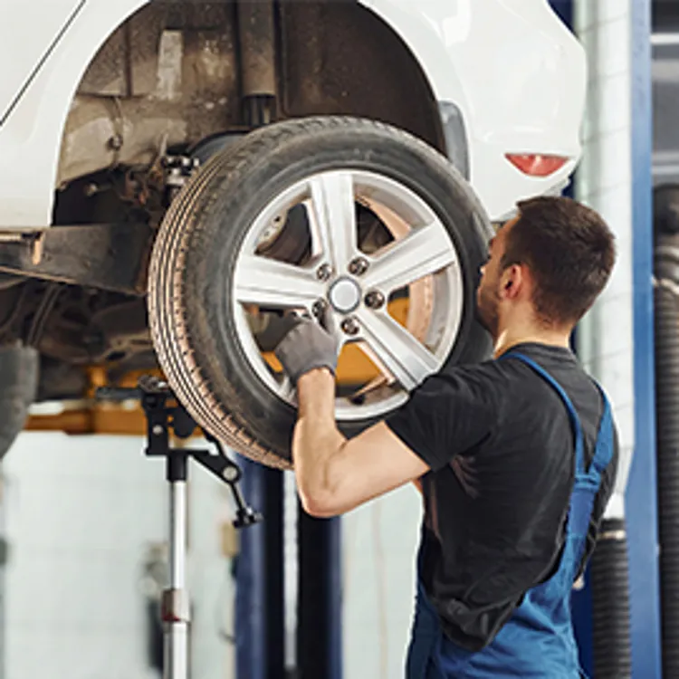 mechanic aligning wheel on vehicle