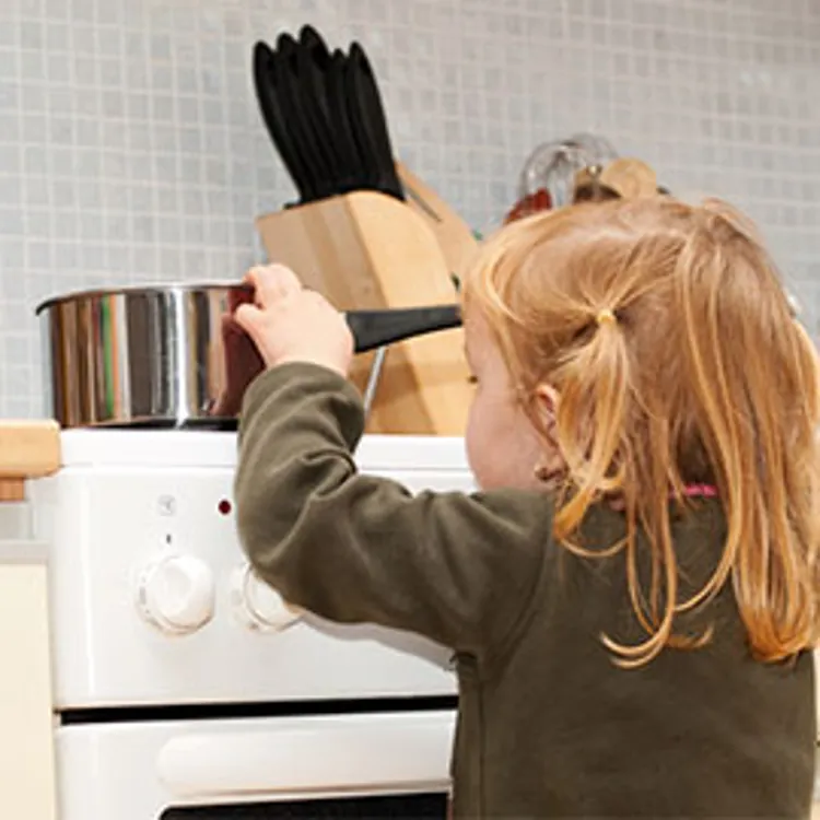 little girl exploring what's in a pot on top of a stove