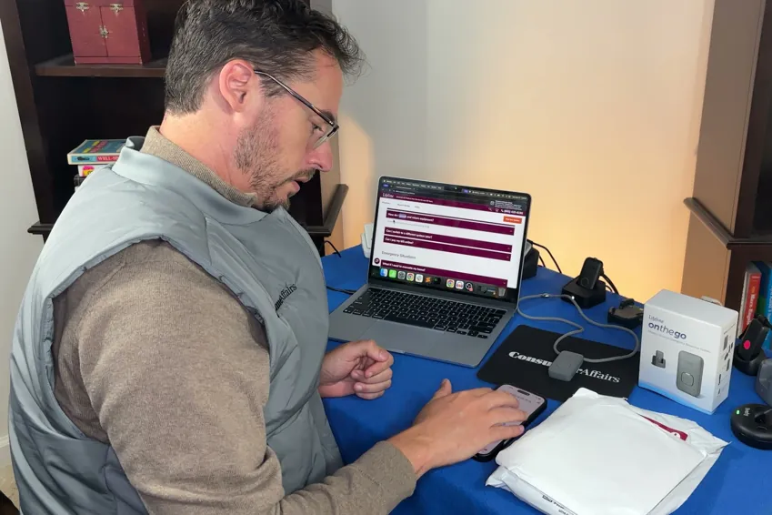 Chris Kolmar at his desk returning the Lifeline system, with medical alert devices, a device box and the contract paperwork on the table