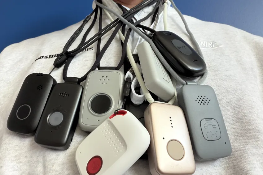 Chris Kolmar wearing nine medical alert pendants on lanyards around his neck over a white sweater
