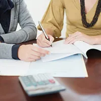 two people signing a document on the table