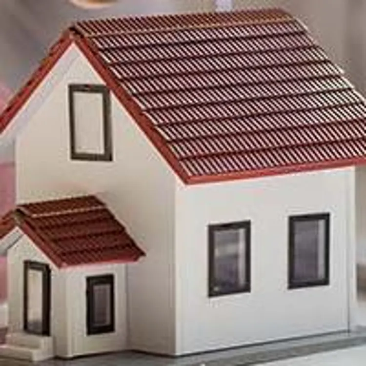 coins being added to piggy bank next to model home