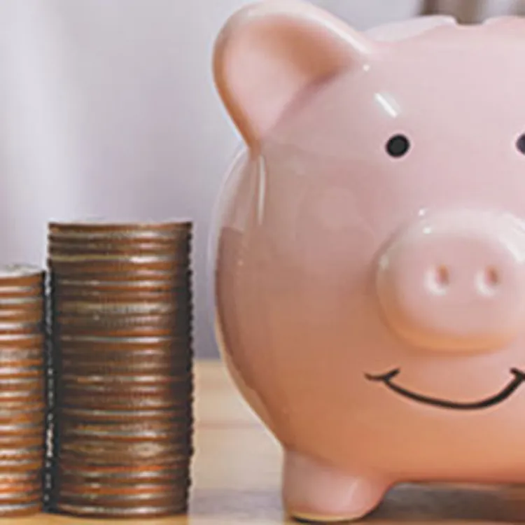 coins stacked next to piggy bank